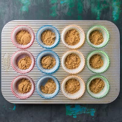Muffin pan with graham cracker crumbs in cups