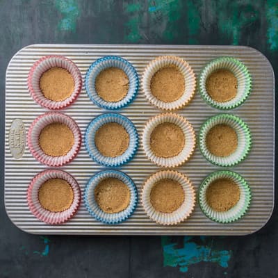 Muffin pan with graham cracker crumbs in cups